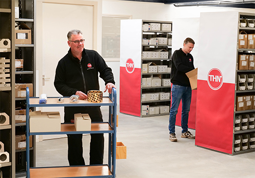 THN warehouse employees picking products between shelves with THN branding