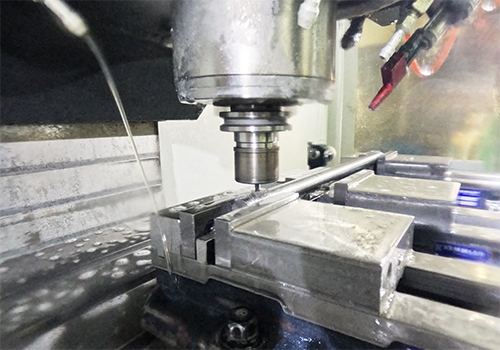CNC frezen van metalen werkstuk in machineklem met koelvloeistof.