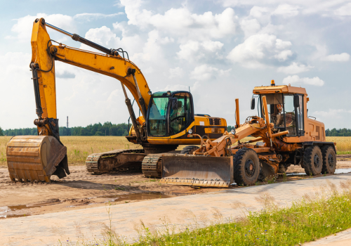 Graafmachine en grader op zandige bouwplaats, voorbereiding wegfundering.